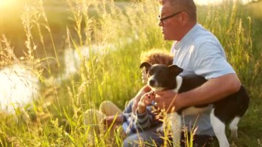 Aile, üretimi, iletişim ve insan kavramı - dede ve torunu ile bir köpek oturuyor ve nehir yatak üzerinde konuşuyor. Mutlu aile tatil