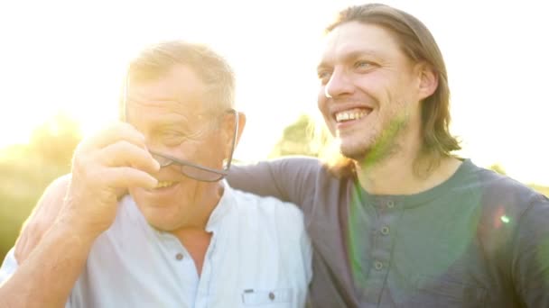 Conversación de hombres. El hijo adulto y el padre anciano se abrazan y se tocan con la frente. Amistad masculina — Vídeo de stock