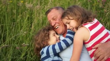 Dede ve torun, bir oğlan ve bir kız, bir ve bir kız bir yaz glade üzerinde bekletin. Torun şen şakrak dedesi sarılmak, çim ve gülmek yatıyordu. Mutlu aile tatil