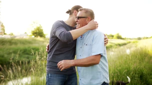 Two generations of one family, father and son. Male friendship. Fathers day. Men stroll along the river bank, hug each other tightly — Stock Video