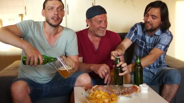 Football fans gathered at home in front of the TV to watch another football match. Men drink beer and support their favorite football team — Stock Video