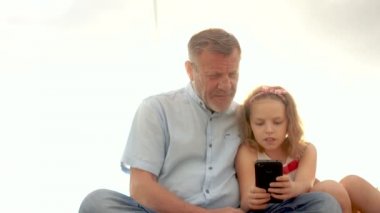 Internet bağımlılığı. Kız ve dedesi telefon ekranında arıyoruz. Aile eğlence