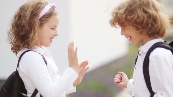 Treffen mit zwei Schülern, einem Jungen und einem Mädchen. Kinder grüßen einander. zurück zur Schule. zum ersten Mal in der Schule — Stockvideo