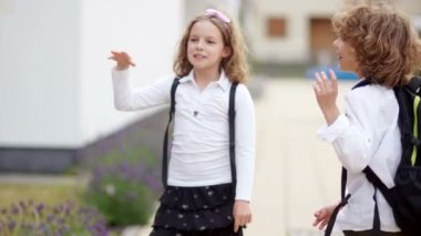 Kıvırcık okul, bir erkek ve bir kız, bir çift veda kameraya bakarak, elinde tutmasına ve bırakarak ellerini sallayarak. Güle güle okul, okul için