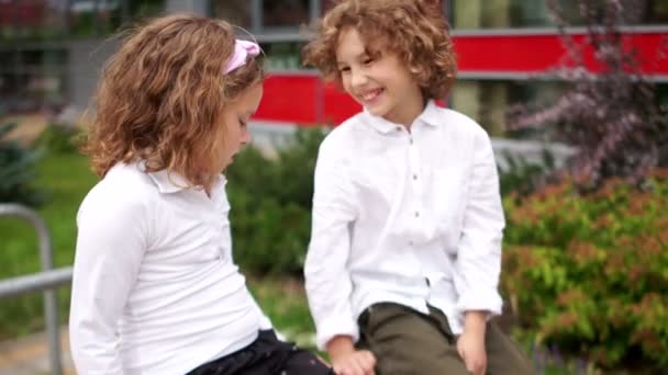 Estudiantes, hermano y hermana, hablando. Niños vestidos con uniforme escolar, con camisas blancas. La chica acaricia suavemente la cabeza de los chicos — Vídeos de Stock