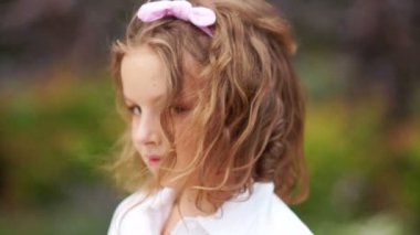 Cilveli bir görünüm kontrol altında. Kahverengi gözlü tatlı kıvırcık kız kameraya doğru coquettishly görünüyor, saçlarını üzerinde pembe bir bandaj var.