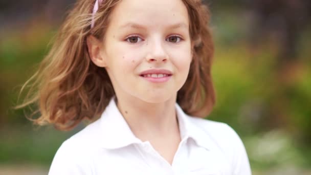 Ragazza dagli occhi castani ricci adolescente guarda la fotocamera e sorride. Gestisce i suoi capelli. Fresca bellezza naturale — Video Stock