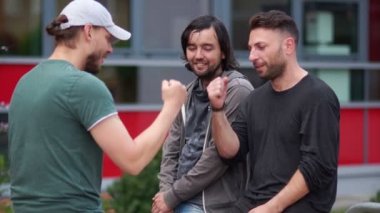 Üç yakışıklı genç erkekler gülümseyen ve konuşurken sakallı. Yakışıklı çocuklar plaing taş-kağıt-makas. Gülmek ve gesticulate