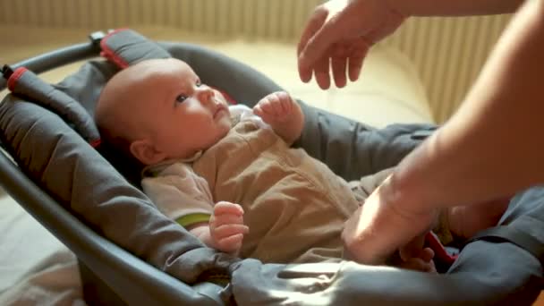 Baby kind vastgemaakt met veiligheid gordel in veiligheid autostoel. De jongen kijkt zijn vader aandachtig en serieus. Kindveiligheid — Stockvideo