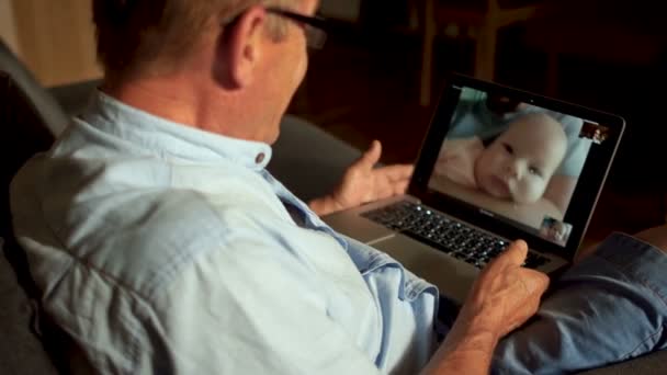 En mogen man pratar med sin vuxen son och nyfödda barnbarn på Skype. Videokommunikation, tre generationer av en familj — Stockvideo