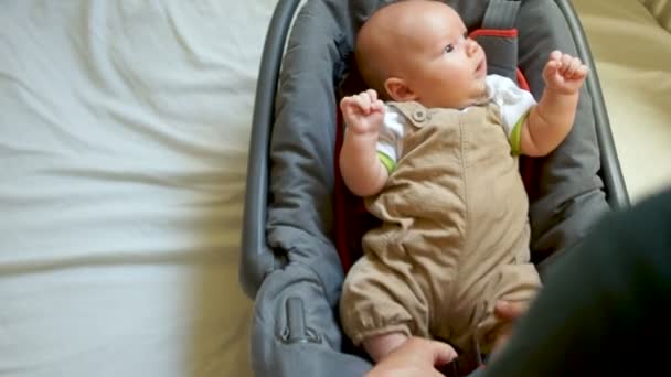Le gamin se prépare à aller se promener. Il porte des ceintures de sécurité dans un siège auto. Sécurité des nourrissons dans le transport routier. Fête des Pères — Video