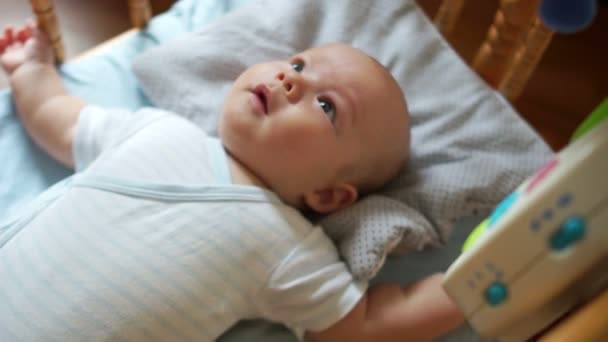 Ein drei Monate altes Kind ist sehr glücklich mit dem neuen Spielzeug. das Kind lacht, zieht an den Beinen und beobachtet seine mobilen Augen — Stockvideo