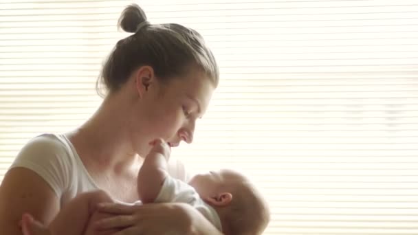 Moeder wiegt haar kind. Ze zingt een slaapliedje voor hem. Moeder en baby zijn in het wit gekleed. Mothers Day — Stockvideo