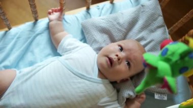 Eğitici oyuncaklar. Çocuk sevinçle yeni oyuncak için tepki verir. Bebek beşik içinde hareket eden. Çocuk oyuncak, hamle, gülümsüyor gözleri izler ve ağız açılır