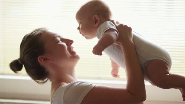 Een gelukkige jonge moeder pakt haar baby. Een drie-maand-oude kind, zorg voor baby's tot een jaar. Mothers Day — Stockvideo