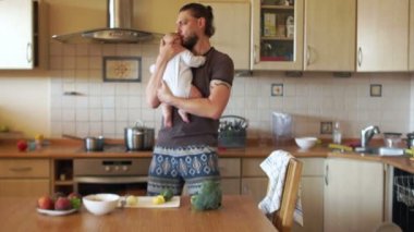 Çekici bir baba oğlunun kollarına holding mutfakta çorba yemek yapıyor. Doğum izni baba
