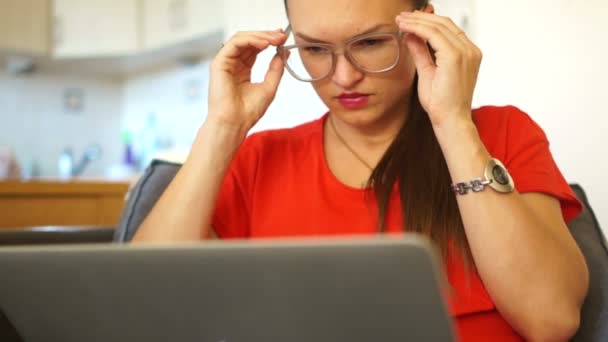 A menina de vermelho está cansada de trabalhar no computador. Ele tira os óculos e esfrega os olhos. Retrato de close-up — Vídeo de Stock