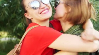 Dinamik video. Parkta bir yürüyüş için güneş gözlüğü güzel kız. Birkaç kız gülmek ve sarılmak. Kırmızı ruj