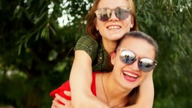 Bir çift güneş gözlüğü gay ve güzel kız gülmek ve aptal yaz parkta oynamak. Arkadaşlık, kız öğrenci
