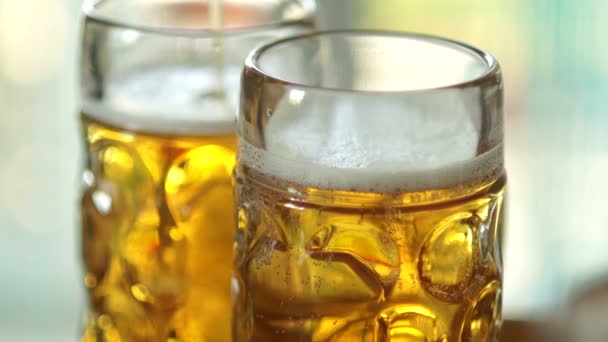 Twee volle glazen, waarin een dun straaltje van koud bier worden getypt. Close-up, zichtbare schuim en lucht belletjes in het glas. Glas glazen verneveld omhoog — Stockvideo