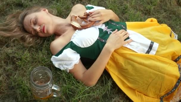 Berusade unga kvinnor liggande på marken. Musikfestivalen oktoberfest. Nära står det ett tomt glas öl och Kringla — Stockvideo