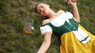 Müzik Festivali oktoberfest. Kız sarhoş bira var ve çim üzerinde uyuyor. Onun yanında bir yarısı boş bardak bira ve cips olduğunu