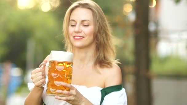 Oktoberfest bira festivali. Geleneksel Bavyera elbiseli Olgun kadın bira içiyor ve utanç verici dudaklarını üzerinde köpük mendil. Kırmızı dudaklar, seksi, erotik — Stok video