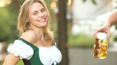 Güzel sarışın Bavyera kız müzik festivali Oktoberfest bira ısmarlar. Kadın mutlu ve gülüyor, o sürpriz ve neşeli.