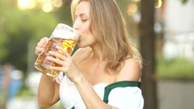 Geleneksel Bavyera elbiseli Olgun kadın bira içiyor ve utanç verici dudaklarını üzerinde köpük mendil. Kırmızı dudaklar, seksi, erotik. Müzikal Oktoberfest bira festivali