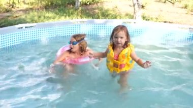 İki kız kardeş bir küçük şişme havuzda yüzmek. Köyün yazın. Mutlu aile, mutlu tatiller