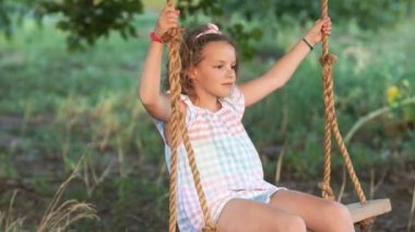 Genç erkek ve kız arasında romantik yaz akşamı seviyorum. İki mutlu çocuk sarılma ve altın gün batımında ahşap salıncak üzerinde sallanan. Kardeşi kucaklayan kardeşim bir salıncak üzerinde
