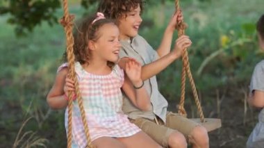 Büyük bir aile. Evlatlık çocuklar. Küçük kız kardeşi onu ve kız bir salıncağa binmek için tatil. Mutlu aile, erkek ve kız kardeşlerim, arasındaki aşk genç çocuk sevgisi