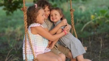 Küçük kız kardeşi onu ve kız bir salıncağa binmek için tatil. Mutlu aile, erkek ve kız kardeşlerim, arasındaki aşk genç çocuk sevgisi