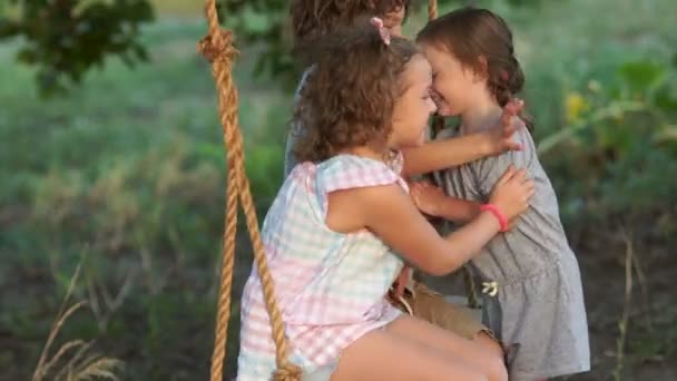 The younger sister resorts to her elder brother and sister to ride on a swing. Happy family, love between brothers and sisters, love of younger children — Stock Video