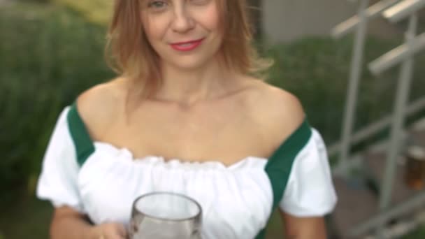 Espuma en un vaso de cerveza. Una chica sostiene un vaso cerca de su pecho. Festival de Música Oktoberfest — Vídeos de Stock