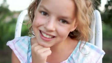 Güzel bir kıvırcık kahverengi gözlü kız portresi. O çenesi için elini tutar ve kamera için poz veriyor. Beyaz Diş gülümseme, kıvırcık saç