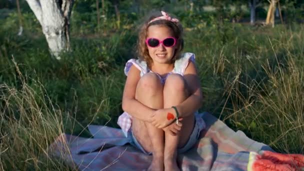Zonsondergang. Einde van de zomer, het einde van de zomervakantie. Een meisje is om te zonnebaden op het gras zitten. Terug naar school — Stockvideo