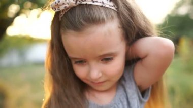 Güzel bir uzun saç ve gri gözleri ile güzel bir küçük kız portresi kapatın. Bebek saç düzeltir ve uzun kirpiklerini düşürür