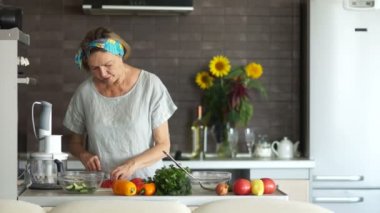 Olgun kadın mutfakta ayakta domates keser. Bir parça çalışır ve onaylayarak sallıyor. Vejetaryen mutfağı, anneler günü. Bir kadın bir aile akşam yemeği hazırlıyor. Şükran günü