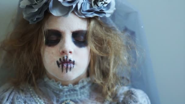 Uma criança vestida de Halloween olha para a câmera e ri. A rapariga da maquilhagem dos mortos. O traje da noiva de Drácula. Celebração do dia dos mortos — Vídeo de Stock