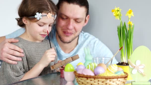 Apa és lánya a tojásfestés. Boldog család készül húsvéti. Aranyos kis gyermek lány visel koszorú — Stock videók