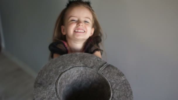 Bambino in costume di Halloween chiede caramelle. Una ragazza tiene in mano un cappello grigio di feltro, il bambino ride felicemente — Video Stock