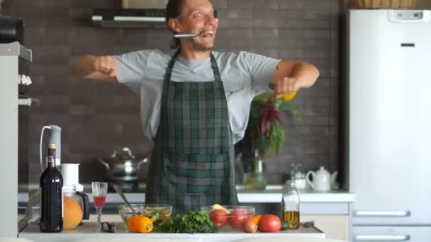 Blue-eyed przystojny mężczyzna taniec nóż w swojej kuchni. Wygłupiać, gotowanie, wszyscy głupcy dnia, poczucie humoru — Wideo stockowe