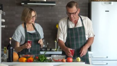 Olgun karı koca mutfak, şarap içeriz, kahkaha ve konuşma bir salata hazırlayın. Romantik bir akşam yemeği, mutlu bir aile