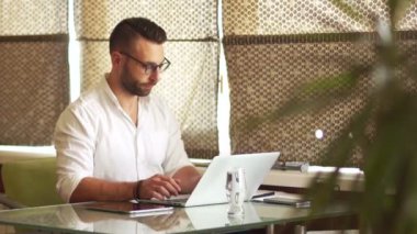 Beyaz gömlek ve gözlük genç işadamı sahip kahve ofiste çalışırken içiyor. Kahve Duraklat