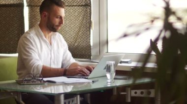 Klasik gömlek ve gözlük yakışıklı işadamı bir dizüstü bilgisayar kullanarak ve ofiste çalışırken odaklı