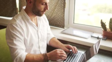 Dinamik portre. Beyaz gömlekli bir adam bir dizüstü bilgisayar üzerinden Internet'e çalışır. Finansal danışmanlık