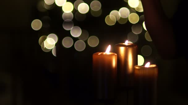 在黑暗的背景上, 用圣诞灯聚焦三支蜡烛。两杯红葡萄酒在手, 两个庆祝圣诞节, 浪漫的夜晚会议, 情人节 — 图库视频影像