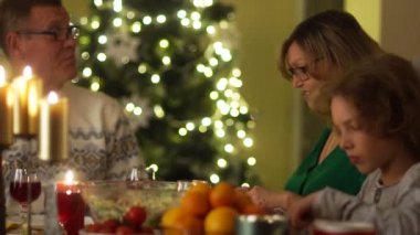 Şükran günü. Ailesi masada toplandı. Yetişkin oğlum tavuk bir tabağa getiriyor. Büyükbaba, Büyükanne, oğlu ve torunu.