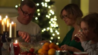 Mum ışığında Noel yemeği. Çocuk bir cam tutar ve bir sürahi üzerinden kırmızı bir komposto dökülür. Mutlu aile, Noel tatili